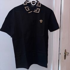 Versace Polo Shirt Size: Medium Color: Black Condition: Never Worn, With Tags Authentic Black Cotton Tops With Collared Neckline, Luxury Short Sleeve Polo Shirt For Work, Designer Black Polo Shirt With Collared Neckline, Designer Fitted Polo Shirt, Designer Fitted Black Tops, Designer Tops With Polo Collar For Workwear, Elegant Black Polo Shirt For Work, Designer Black Polo Shirt For Work, Luxury Black Shirt For Work