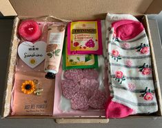 an open box containing socks, candles, and other personal care items with flowers on them