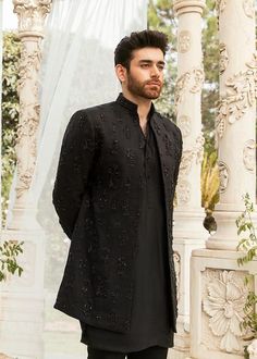 a man standing in front of a white gazebo wearing a black shirt and pants