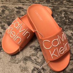 I Have Womens Sizes 6 And 7. These Are Calvin Klein Style Axel Logo Slides. Perfect For The Pool Or Around The House. Comfortable, Durable, And Stylish Slides To Go About Your Day In. The Color Is A Nice Salmon, These Are Unisex Trendy Calvin Klein Sandals For Spring, Calvin Klein Slip-on Sandals For Summer, Calvin Klein Casual Sandals With Cushioned Footbed, Casual Calvin Klein Sandals With Cushioned Footbed, Calvin Klein Casual Slip-on Sandals, Calvin Klein Casual Sandals For Summer, Casual Calvin Klein Slip-on Sandals, Casual Calvin Klein Sandals For Summer, Orange Flat Slides For Spring