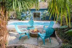 three chairs sitting around a fire pit in the middle of a backyard with a pool