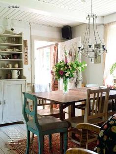 the dining room table is surrounded by chairs and vases with flowers in them,