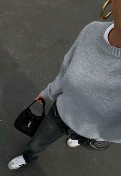 a woman is walking down the street with her hand on her hip and holding a black purse