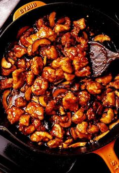 a skillet filled with chicken and sauce on top of a stove burner next to an orange spatula