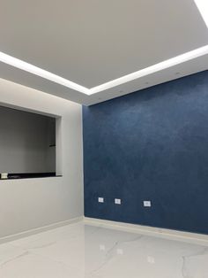 an empty room with blue walls and white floors