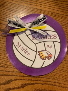 a purple plate with a ribbon on it that says eagle's and has a volleyball in the middle