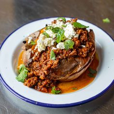 a white plate topped with an eggplant covered in sauce and feta cheese