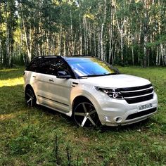 a white suv parked in the middle of a forest