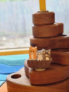 a wooden tower with two cats sitting on it's sides and another cat figurine next to it