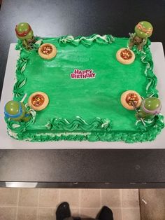 a green sheet cake with teenage mutant figures on it's sides and the words happy birthday