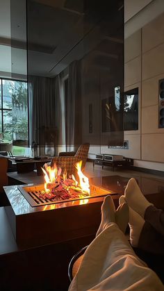 a person laying down in front of a fire place with their feet on the table