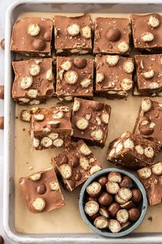 a pan filled with brownies and nuts next to a bowl of chocolate candies