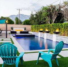 two lawn chairs sitting next to a swimming pool in the middle of a backyard area