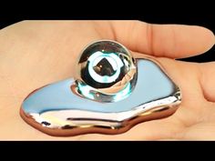 a hand holding a shiny metal object in it's left hand, with an eyeball on top