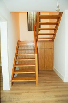 a wooden stair case next to a white wall