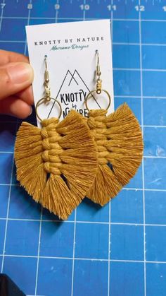 a pair of tasseled earrings sitting on top of a blue counter next to a piece of paper