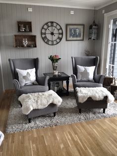 a living room with two chairs and a footstool in front of a clock