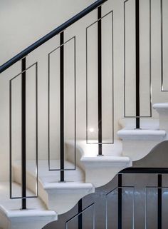 a white staircase with black handrails and glass balconies