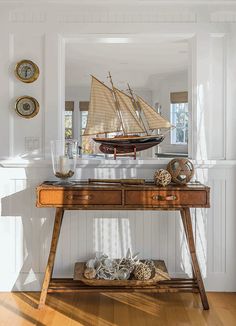 a wooden table topped with a boat on top of it next to a wall mounted clock