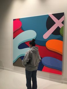 a woman standing in front of a colorful painting