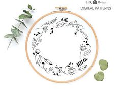 an embroidery pattern with flowers and leaves on it, next to two green plants in front of the hoop