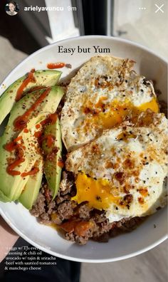 an egg is on top of some meat and avocado in a white bowl