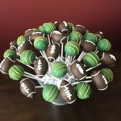 a bowl filled with green and white chocolate covered cake pops on top of a wooden table