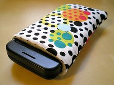 a cell phone case sitting on top of a wooden table covered in polka dot fabric