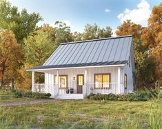 a small white house with a metal roof in the middle of some trees and grass