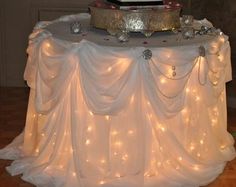 a table topped with a cake covered in white frosting and lite up lights