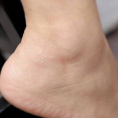 a small white star tattoo on the side of a person's foot and ankle