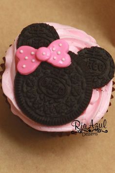 the cupcake is decorated with pink icing and minnie mouse ears on it's head