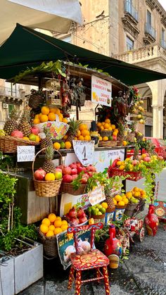 an outdoor fruit stand with oranges, apples and other fruits