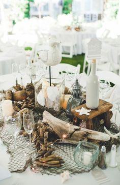 the table is set with candles, wine bottles and driftwood for an outdoor wedding reception