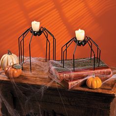 three candles are placed on top of a table with spider webs and pumpkins