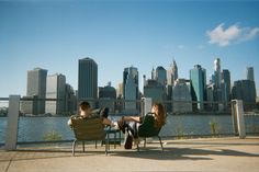 two people sitting on lawn chairs in front of a city skyline