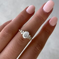 a woman's hand with a three stone engagement ring on her left and an oval shaped diamond in the middle