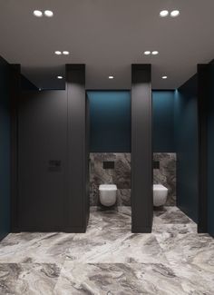 two urinals in the middle of a bathroom with blue walls and marble flooring