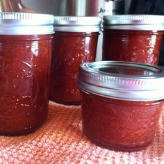 four jars filled with jam sitting on top of a counter