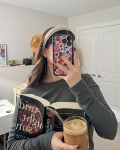 a woman is holding a book and looking through a magnifying glass at her phone