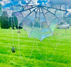 a spider web hanging from the side of a wind chime in a grassy field