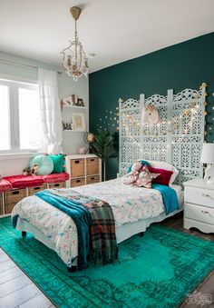 a bedroom decorated in teal and gold with a bed, dressers, chest of drawers and rug