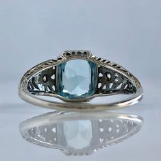 Details: Beautiful Edwardian Aquamarine & Diamond 18K white gold filigree ring. The ring has a sweet floral pattern on the sides of the filigree, and the diamonds are the center of the side flowers. The aquamarine measures 9mm x 7mm, and the two diamonds measures 2mm each. The ring is stamped 18K on the inside of the band. Measurements: Ring measures a size 7 1/4 US. It can be re-sized for a fee. Condition: The overall all condition of this ring is very good, with some very slight wear on th Vintage Platinum Ring With Gemstone, Antique Platinum Gemstone Rings, Antique Platinum Ring With Gemstone, Antique Platinum Rings With Gemstone, Luxury Formal Filigree Ring With Rose Cut Diamonds, Antique Cushion Cut Rings For Formal Occasions, Elegant Engraved Diamond Ring For Formal Occasions, Vintage Platinum Gemstone Jewelry, White Gold Art Deco Topaz Ring With Center Stone