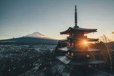 the sun is setting behind a tall building with a pagoda on it's roof