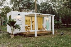 a small white house sitting in the middle of a forest