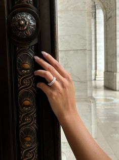 a woman's hand on the door handle of an ornately decorated building with columns and arches