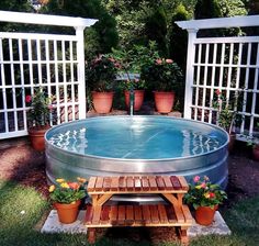 an outdoor hot tub surrounded by potted plants and wooden benches with latticed arbors