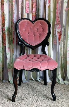 a pink chair with a heart shaped back rest on carpeted floor next to curtains