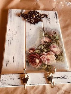 an old white wooden box with flowers painted on the front and sides, hanging from hooks