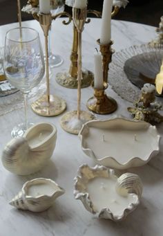 a table topped with white dishes and candles